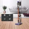 A cordless vacuum cleaner displayed on its charging stand in a living room setting. Voir les images du produit