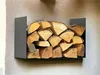 A black metal firewood rack mounted on a textured wall, filled with logs. Produktbild-Vorschau
