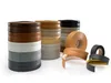 Several stacks of flexible PVC edge banding in various colors and wood grain patterns are displayed on a white background. Some rolls of edge banding are also shown unrolled. Produktbild-Vorschau