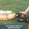 A hand holding a black and orange cordless air pump connected to an inflatable pool on a grassy lawn. Produktbild-Vorschau