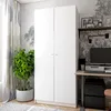A white two-door wardrobe is shown in a room setting with a plant and a desk. Náhled obrázku produktu