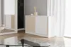 A modern white sideboard with wooden slatted doors is shown in a well-lit room with a large window and white curtains. Náhľad obrázku produktu