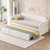 A white daybed with a pull-out trundle bed is shown in a room with decorative wall art and a plant. Podgląd zdjęcia produktu
