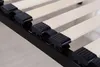 Close-up view of a bed frame's wooden slats and black plastic holders. Produktbild-Vorschau