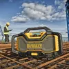 A construction worker in a hard hat and safety vest looks at his phone while a DeWalt radio sits on rebar at a construction site. Voir les images du produit