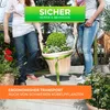 Two people are carrying a large potted plant using a strap system. Produktbild-Vorschau