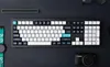 A top-down view of a mechanical keyboard and accessories on a dark surface. Produktbild-Vorschau