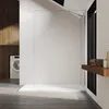 A modern bathroom with a walk-in shower, washing machine, and wooden accents. Voir les images du produit