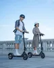 A man and a woman riding electric scooters outdoors. Produktbild-Vorschau