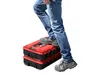A person's legs and feet are shown stepping on a stack of two red and black toolboxes. Anteprima dell’immagine prodotto