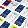 A collection of Monopoly game cards laid out diagonally on a light gray surface. Produktbild-Vorschau