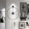 A large, minimalist wall clock is the focal point of this image, displayed on a white wall in a modern interior setting. Several framed pictures and a pendant lamp are also visible, contributing to the overall aesthetic. Anteprima dell’immagine prodotto