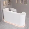 A white reception desk with a fluted front and LED lighting at the base, placed on a concrete floor in a modern interior. Produktbild-Vorschau