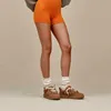 A person wearing orange shorts, white socks, and brown sneakers. Produktbild-Vorschau