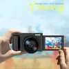 A hand holding a black digital camera with a flip-out screen showing a group of people. Náhľad obrázku produktu