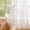 A bright room with a window covered by sheer curtains with cloud patterns. A lamp and a basket are on the windowsill. Produktbild-Vorschau