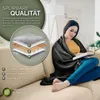 A woman is sitting on a couch, reading a book and wrapped in a dark gray blanket. Produktbild-Vorschau