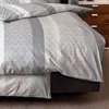 A close-up view of a bed with grey and white striped bedding. Produktbild-Vorschau