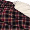 A close-up view of a plaid blanket with a fluffy white lining. Produktbild-Vorschau