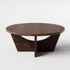 A round, dark wood coffee table with a unique base. Produktbild-Vorschau
