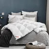 A neatly made bed with a white duvet and several pillows. Produktbild-Vorschau