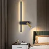 A modern bedroom with a bedside table and a wall lamp. Produktbild-Vorschau