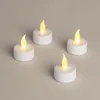 Four white LED tea lights with yellow flames are arranged on a light gray surface. Anteprima dell’immagine prodotto
