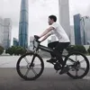 A man rides an electric bicycle in a city with tall buildings in the background. Produktbild-Vorschau