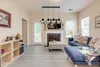 A living room with a blue sofa, fireplace, and a multi-light pendant lamp. Produktbild-Vorschau
