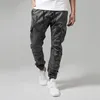 A person is standing and modeling camouflage cargo pants. Produktbild-Vorschau