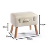 A white upholstered footstool with wooden legs, designed to resemble a vintage suitcase, is shown against a white background with measurement indicators. Náhled obrázku produktu