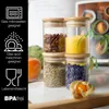 Four glass jars filled with spices and dried ingredients, stacked in two columns, with informational icons on the left. Produktbild-Vorschau
