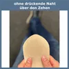 A person is holding up a beige sock in front of their legs, which are clad in blue jeans. The background is a blurred indoor setting. Produktbild-Vorschau