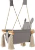 A baby swing with bunny ears and tassels, suspended by ropes. Náhled obrázku produktu