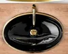 A top-down view of a black oval sink with a gold rim and faucet, placed on a wooden surface. Produktbild-Vorschau
