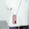 A person wearing a fluffy white sweater and purple pants, with a pink phone case with a lanyard hanging around their neck. Produktbild-Vorschau