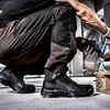 A person wearing work pants and safety boots is using an angle grinder. Produktbild-Vorschau