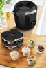 A black multi-cooker is shown on a wooden countertop, with a steaming rack and several small dessert cups in the foreground. Voir les images du produit