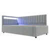 A light gray upholstered bed frame with a channel-tufted headboard and integrated LED lighting. Produktbild-Vorschau
