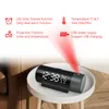 A digital alarm clock with a projection feature is displayed on a small white table, with red projection lines emanating from it. Podgląd zdjęcia produktu