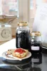 Jars of jam and a scone with jam on a kitchen counter. Podgląd zdjęcia produktu