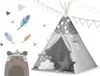 A children's teepee tent with decorative elements like stars, pom-poms, and string lights, set against a white background with cartoonish tribal-themed graphics. Produktbild-Vorschau