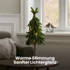 A small LED-decorated Christmas tree sits on a table next to a sofa with a blanket. Produktbild-Vorschau