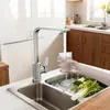 A person is filling a glass with water from a kitchen faucet into a sink with vegetables. Produktbild-Vorschau