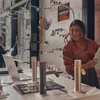 A woman is looking at a display of faucets and showerheads in a showroom, with a laptop on the counter. Produktbild-Vorschau