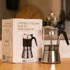A coffee maker and its packaging are displayed on a wooden table. Produktbild-Vorschau