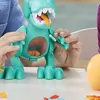 Close-up of hands playing with a teal dinosaur toy that has an orange tongue sticking out and small orange pieces inside its transparent belly. Náhled obrázku produktu