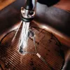 A grill brush is being used to clean a grill grate under running water in a sink. Produktbild-Vorschau