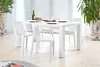 A white dining table with chairs set in a dining room with blinds and plants. Produktbild-Vorschau