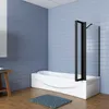 A modern bathroom with blue tiled walls, a white bathtub with a black framed glass shower screen, and a wooden stool with a blue rug on the floor. Produktbild-Vorschau